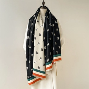 Detailed view of thick cashmere scarf featuring black and white H pattern and fringe edges