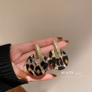 Detailed shot of leopard print resin earrings with hammered gold metal textured accents