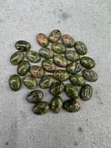 Overhead macro view of polished oval green aventurine stones with reddish jasper patterns