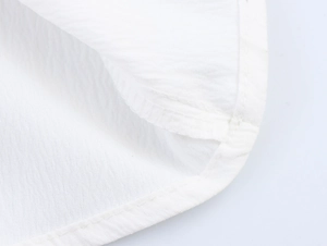 Detailed macro shot of fine stitching and cotton texture on white holiday dress