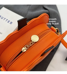 Detail of smooth gold zipper and orange Saffiano leather on the pumpkin shoulder bag