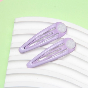 Close-up of a pair of purple metal snap hair clips with white polka dot patterns on base