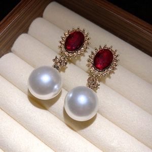 Close-up of vintage drop earrings with red crystal, rhinestones and white pearls