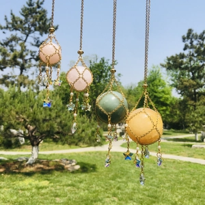Hanging crystal ball net pendants in pink green and yellow with gold chains outdoors