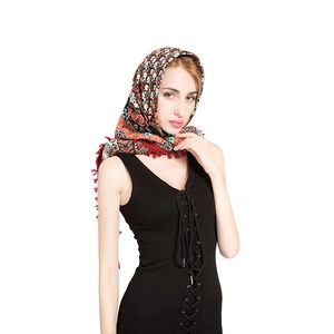 Detail of bohemian scarf showing ethnic floral patterns and red knotted tassels
