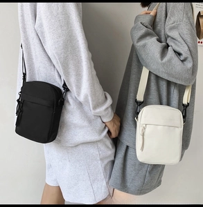 Detail of trendy nylon crossbody bag featuring double zipper pockets and adjustable strap