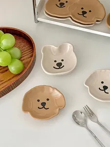 Close-up of cute bear and puppy ceramic sauce dishes on a wooden tray with grapes