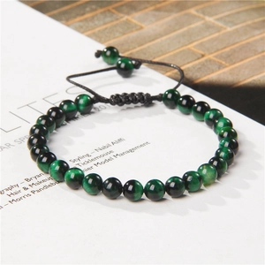 Detail of 6mm green tiger eye stone beads on a black woven adjustable bracelet