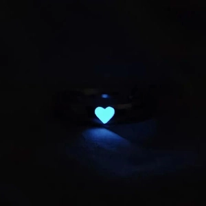 Luminous heart-shaped glow-in-the-dark ring with blue light in dark environment