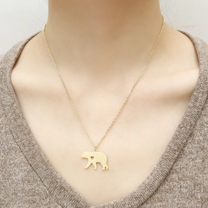 Close-up of golden bear pendant with heart cut-out on a woman's neck