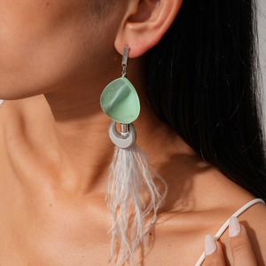 Detail of bohemian green resin earrings with white feather tassels on model