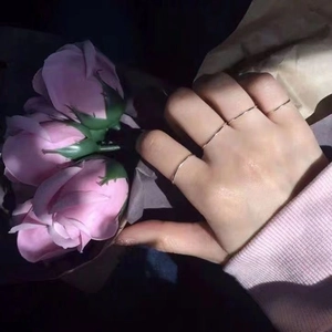 Detail von minimalistischen silbernen Stapelringen, getragen mit einer Rosenblüte