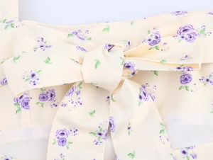 Détail d'une robe en satin à fleurs avec motif rose violet et nœud décoratif délicat
