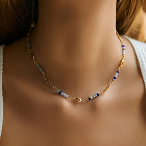 Detail of bohemian beaded necklace with heart charms and blue beads on model neck