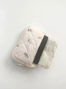 Detailed view of beige quilted cotton pouch with floral patterns and snap closure