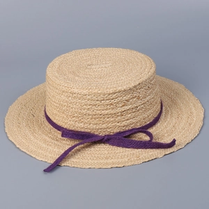 Detailed view of raffia flat-top straw hat with elegant purple bow decoration.