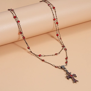Macro detail of gothic double-layer cross necklace with red rhinestones and vintage finish