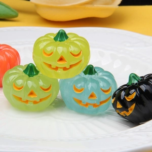 Macro shot of colorful luminous pumpkin resin charms on a white decorative plate