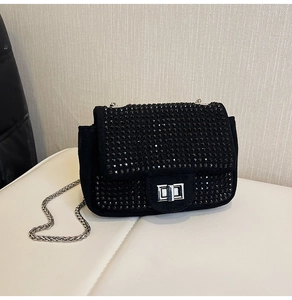 Macro view of black suede evening bag with glittering rhinestones and silver turn lock