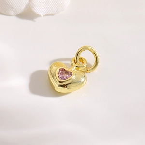 Macro detail of 18k gold plated copper heart pendant with a pink zircon stone inlay