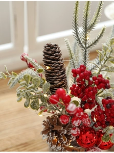 Detail of Christmas table decor with snowy pine cones, red berries and warm LED lights