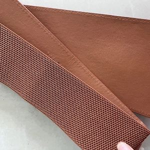 Detail shot of reddish brown wide corset belt showing PU leather texture and elastic band