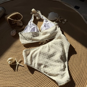 Detailed flat lay of cream shell-texture high-waisted bikini with starfish and beach decor