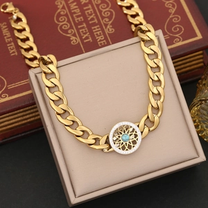 Macro shot of gold Cuban link bracelet with green turquoise pendant on beige jewelry box