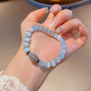 Detailed close-up of light blue cat eye stone bracelet with pearl and waterdrop pendant