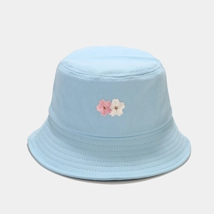 Detailed view of pink and white cherry blossom embroidery on a light blue cotton bucket hat
