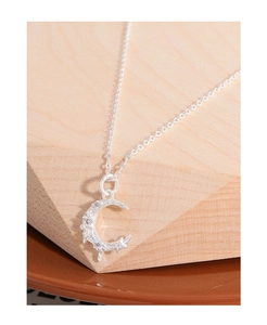 Macro shot of silver crescent moon necklace with textured surface and zircon stones