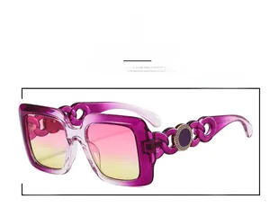 Macro detail of purple square sunglasses with gold Greek key motif and chain temples