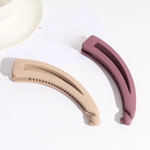 Detail of matte cream and purple banana hair clips in a minimalist lifestyle setting