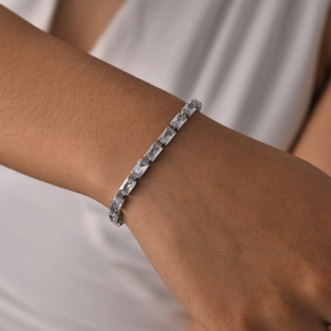 Elegant silver metal bracelet with rectangular clear zircon stones on a model's wrist