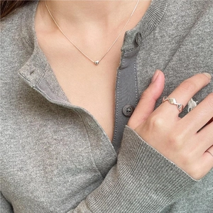 Detail showing 925 sterling silver heart necklace and wavy ring on a model