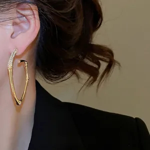 Chic gold bamboo curved hoop earrings with sparkling crystal accents for women