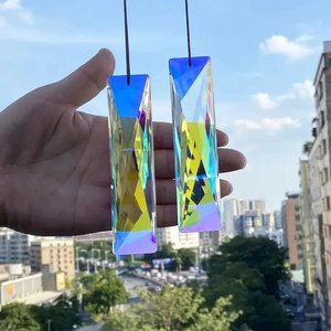 Macro shot of two long K9 crystal suncatcher prisms with rainbow coating held against sky