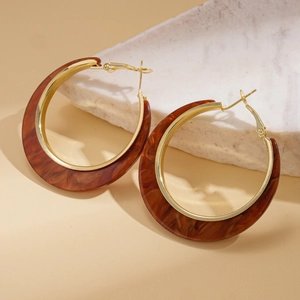 Macro detail of large amber resin hoop earrings with gold metal on a stone base