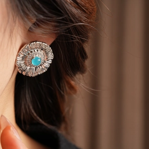 Close-up of vintage flower earrings with blue gemstone and shimmering zircon petals