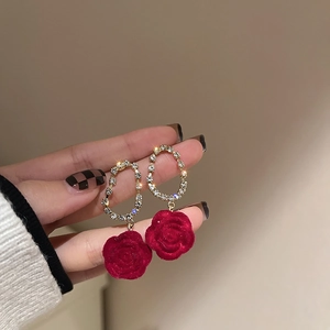 Close-up of velvet red rose drop earrings with sparkling rhinestones and gold oval loops