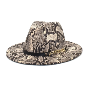 Detail of snakeskin fedora hat with black band and gold chain accent on white background