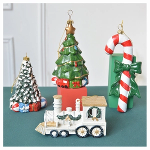 Detail of resin Christmas ornaments featuring a candy cane and retro train with snow finish
