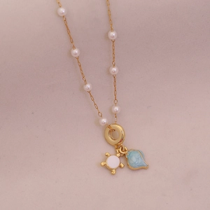 Golden turtle and pearl necklace with light blue shell pendant on soft pink background
