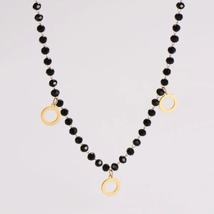 Detailed view of faceted black beads and gold circular hollow pendants on an elegant necklace
