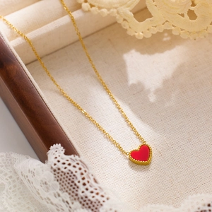 Golden heart necklace with red enamel pendant and Roman numerals on a jewelry box