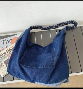 Detailed texture of dark blue washed denim hobo bag with thick woven shoulder strap