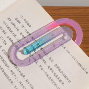 Macro detail of large paperclip-shaped resin bookmark in pink and blue gradient on a book