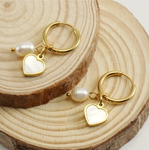 Détail de boucles d'oreilles cœur en or avec perles sur présentoir en bois naturel