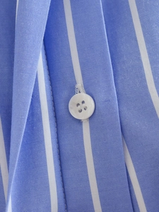 Gros plan d'une chemise à rayures bleues et blanches avec boutons en résine blanche