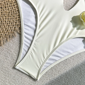 Detailed close-up of cream cutout swimsuit featuring 3D floral accent and mesh lining
